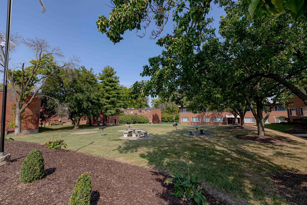a park with trees and a courtyard in front of a brick building