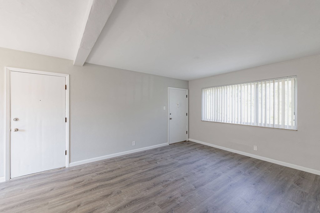 an empty living room with white walls and wood floors