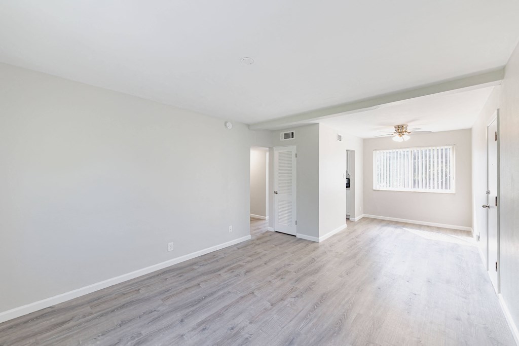 an empty living room with white walls and wood flooring