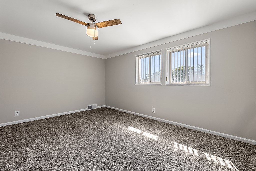 a bedroom with two windows and a ceiling fan