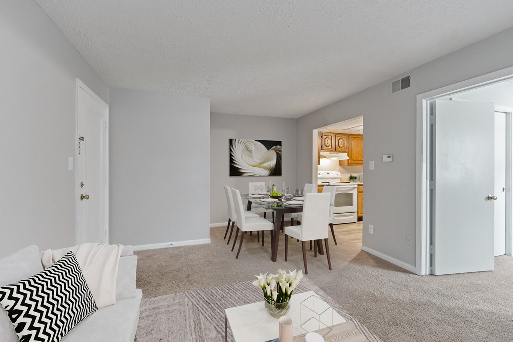 a living room with a dining room table and a kitchen in the background