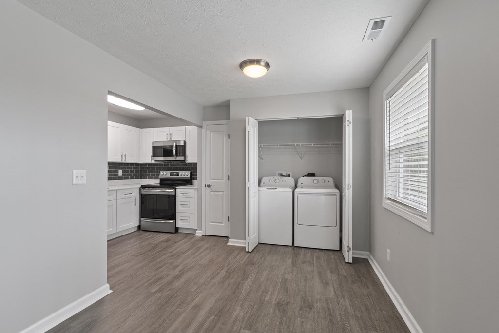 the interior of a studio apartment with a kitchen and laundry room