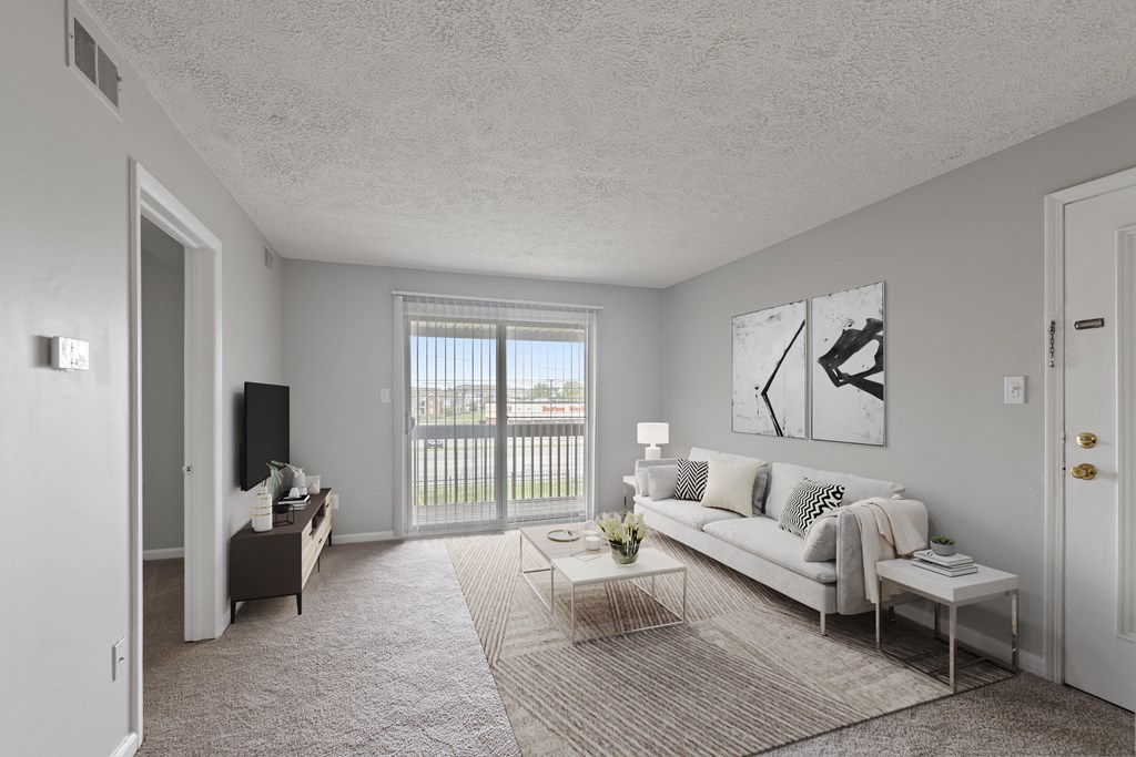 a spacious living room with a sliding glass door leading to a balcony
