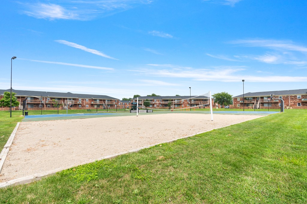 a sand volleyball court with a building in the background