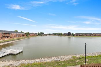 a view of a lake with a dock and apartment buildings in the background