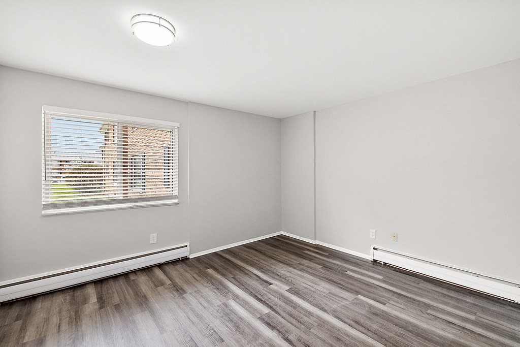 a bedroom with hardwood floors and a large window