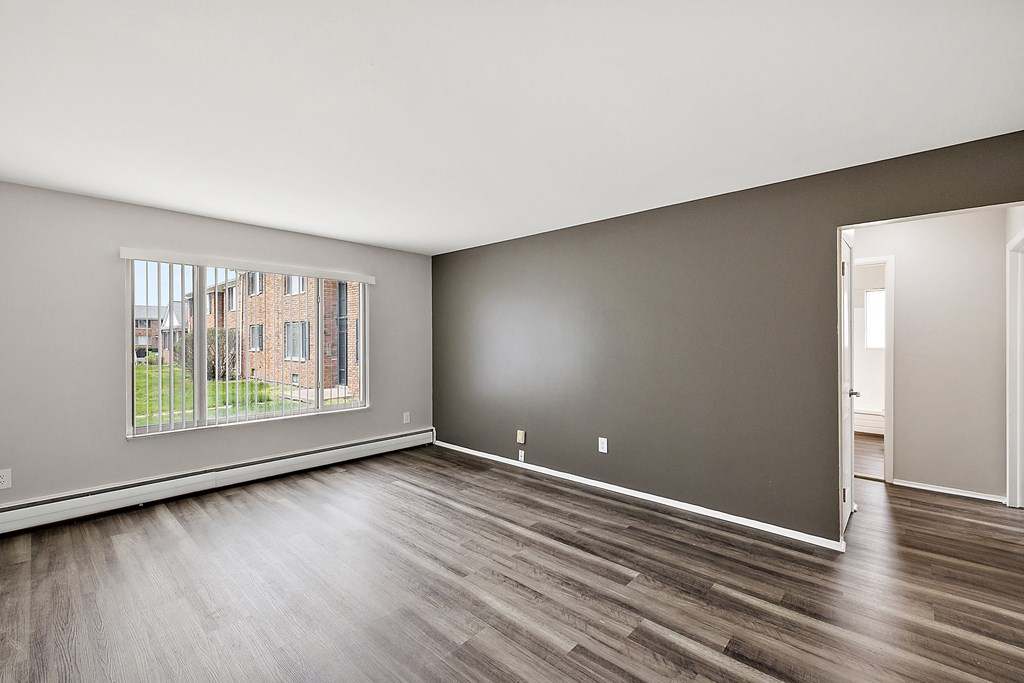 a bedroom with a large window and hardwood floors