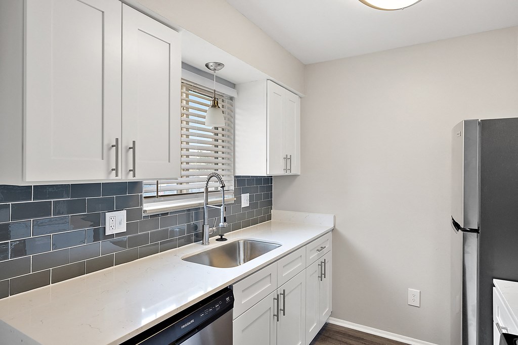 a kitchen with white cabinets and a black dishwasher