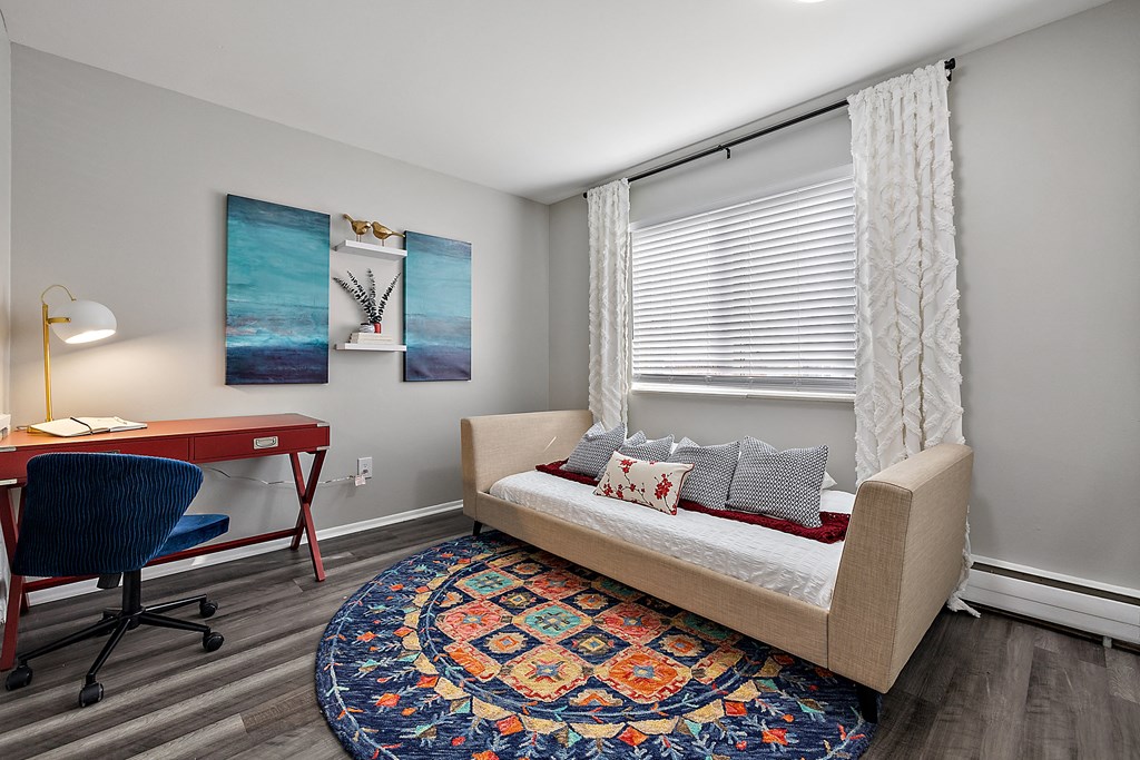 a bedroom with gray walls and a red desk with a blue chair in front of a window