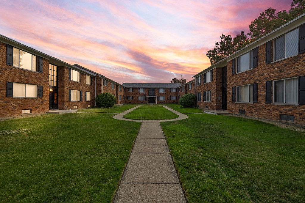 a pathway leads through a grassy area in front of a brick building
