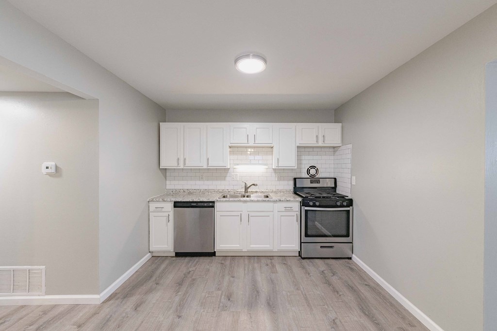 a kitchen with white cabinets and stainless steel appliances