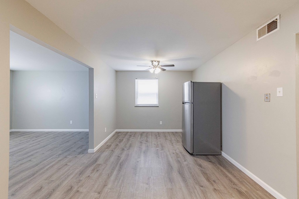 an open living room with a refrigerator in the corner