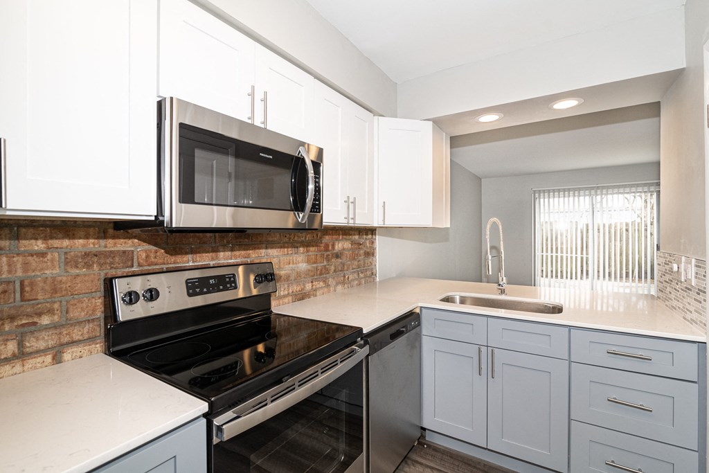 an empty kitchen with white cabinets and a stove and microwave