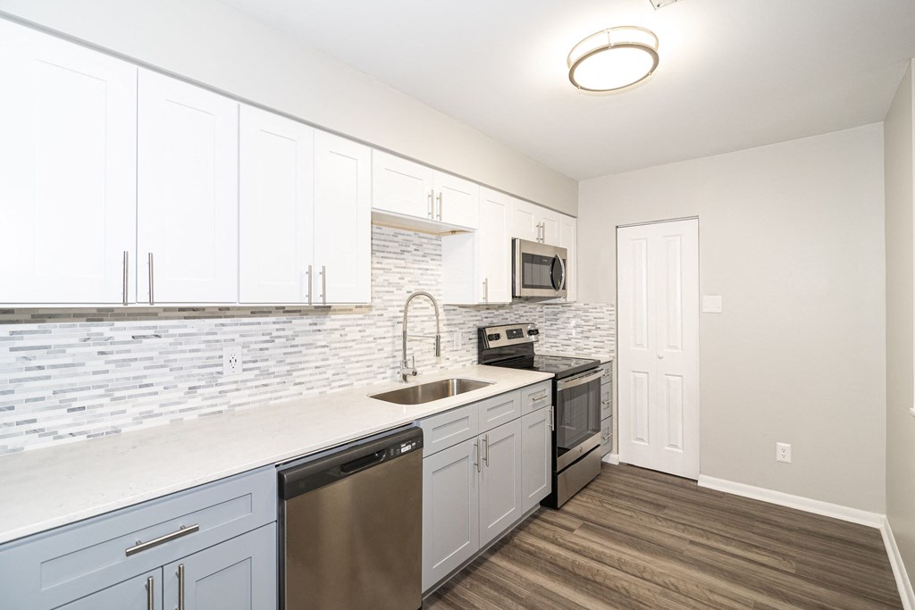 an empty kitchen with white cabinets and a stainless steel sink