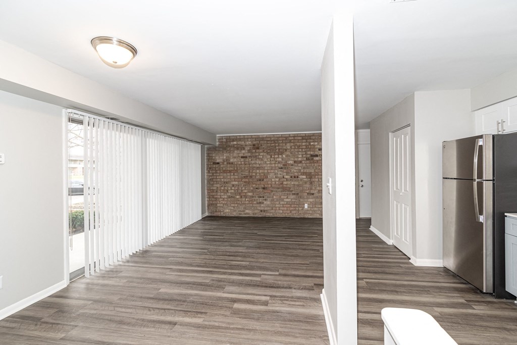 a renovated living room with a large window and a stainless steel refrigerator
