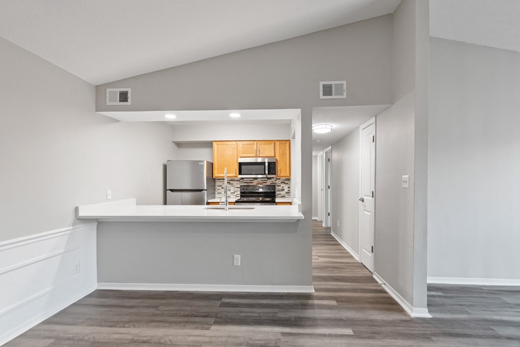 the living room and kitchen in a new home with white walls and wood floors