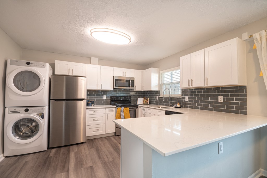 a kitchen with white cabinets and a white counter top and a stainless steel washer and dry