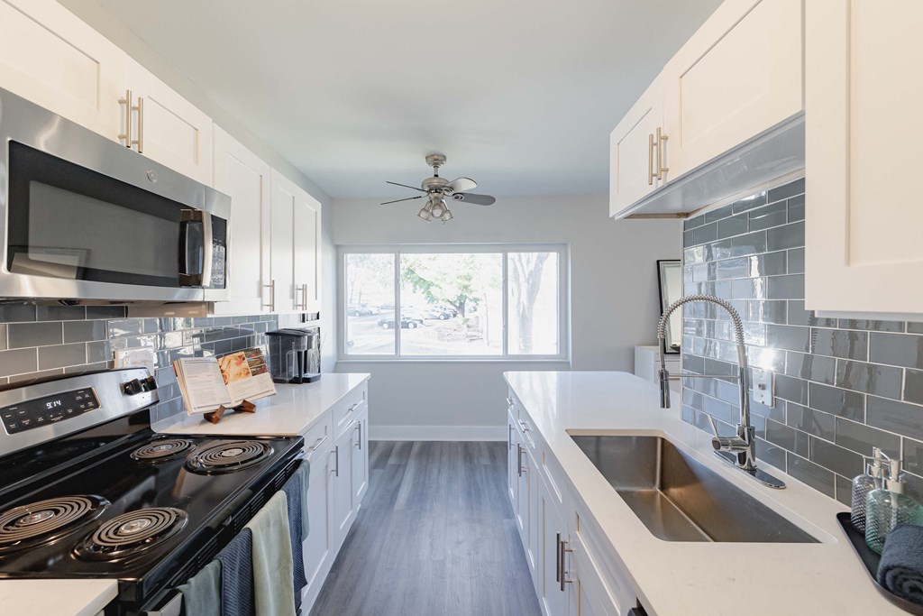 a kitchen with white cabinets and black appliances and a sink