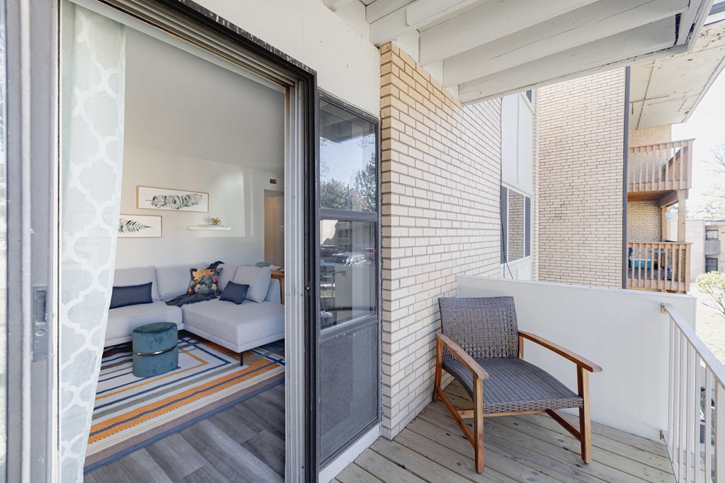 a balcony with a couch and a chair and a sliding glass door