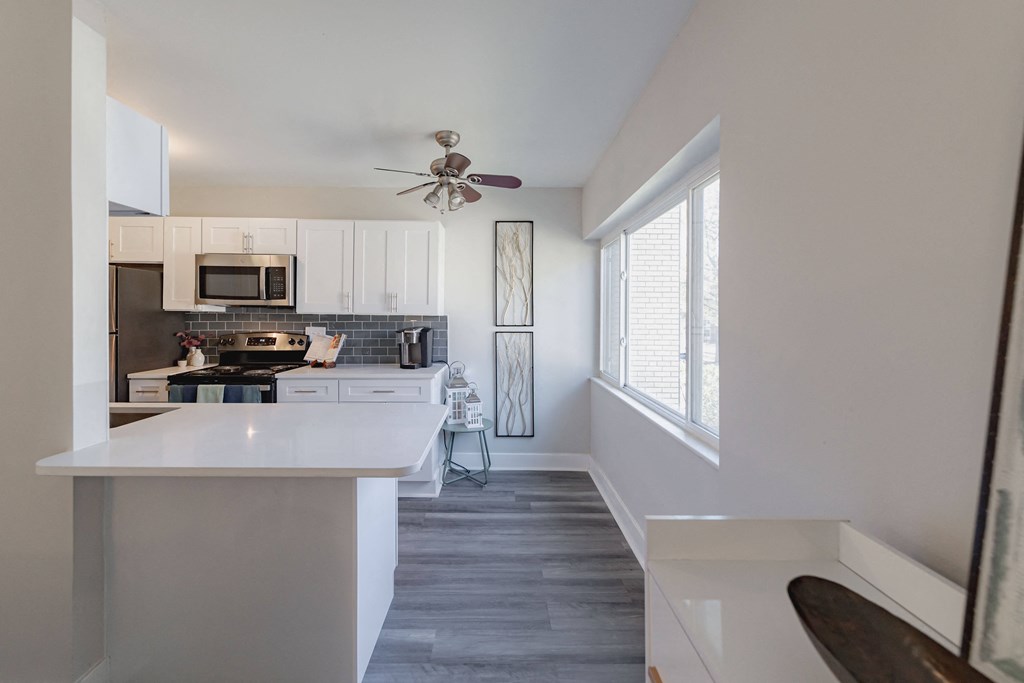 a kitchen with white cabinets and a large window and a white counter top