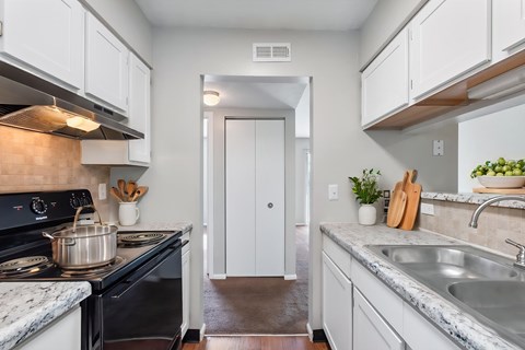 A kitchen with a black stove top oven and white cabinets.