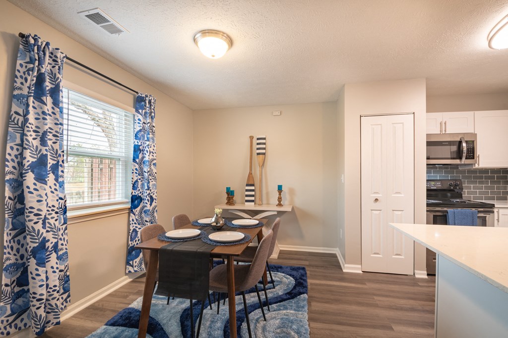 a dining area with a table and chairs and a kitchen in the background