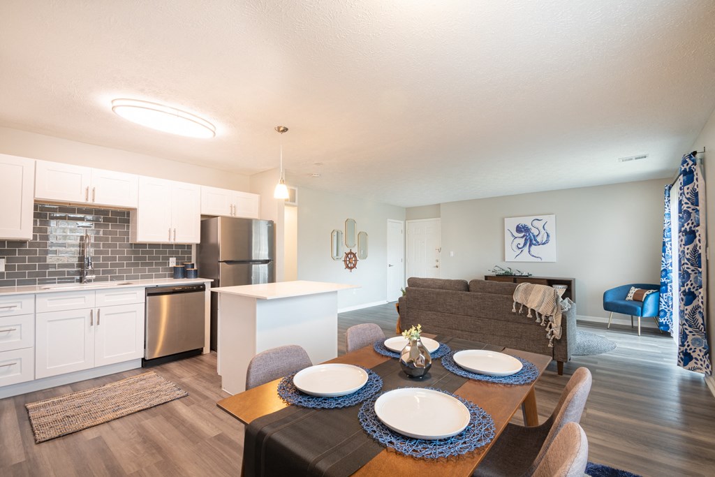 an open floor plan with a dining table and chairs and a kitchen with stainless steel appliances