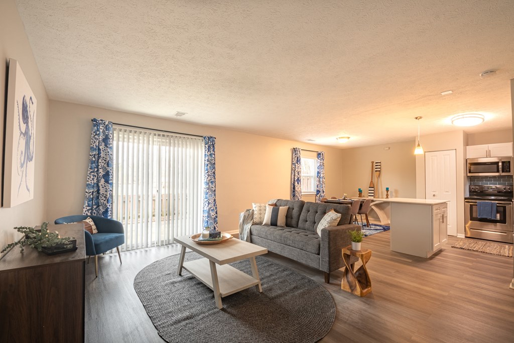 a living room with a couch coffee table and a kitchen in the background