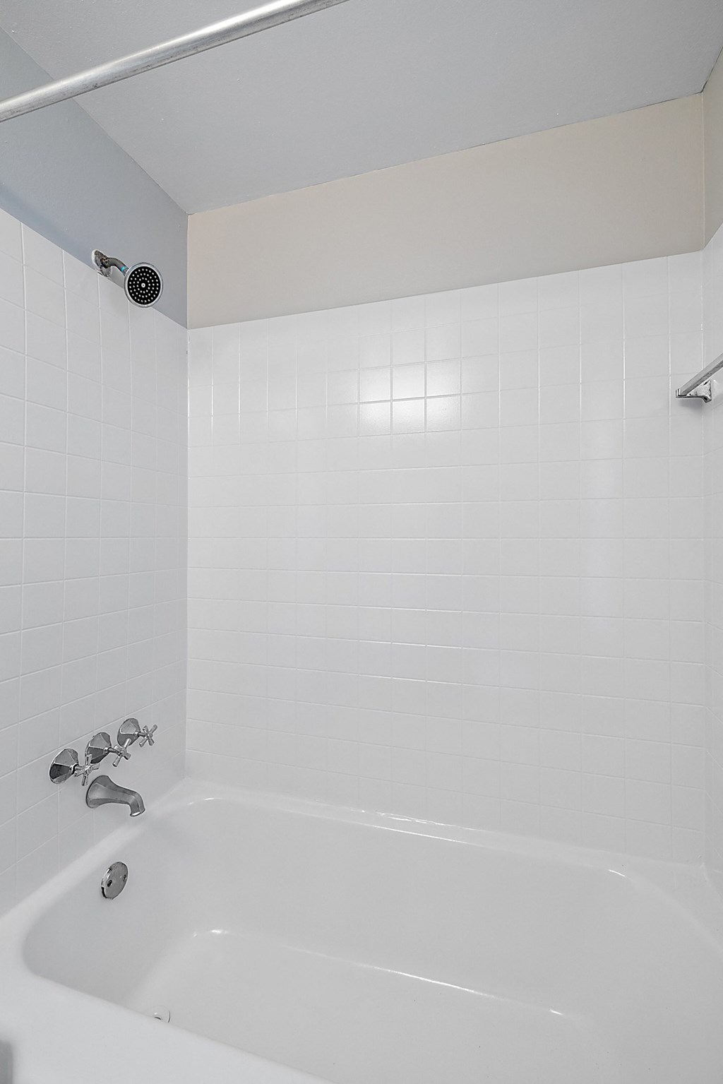 a bathroom with a white tub and a white tiled wall