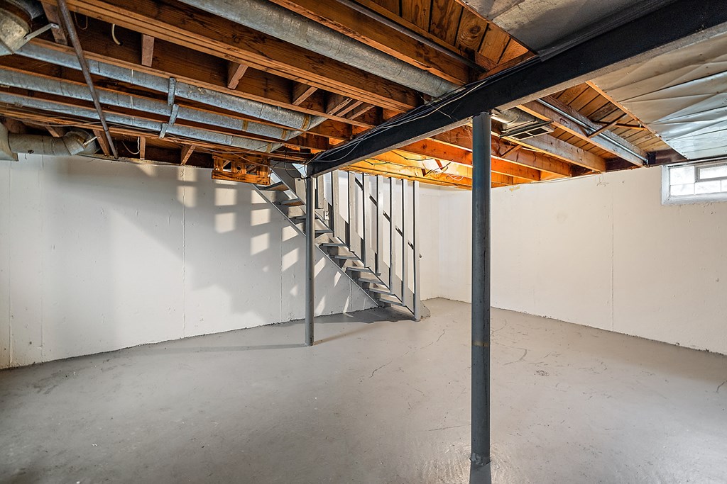 a basement with a staircase and a white wall
