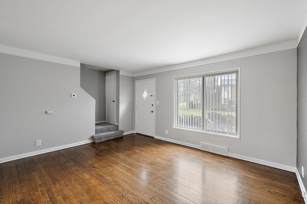 a bedroom with a large window and hardwood floors