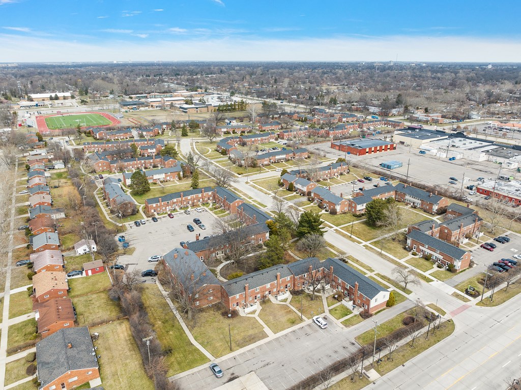 an aerial view of a neighborhood with several houses and a baseball field in the background