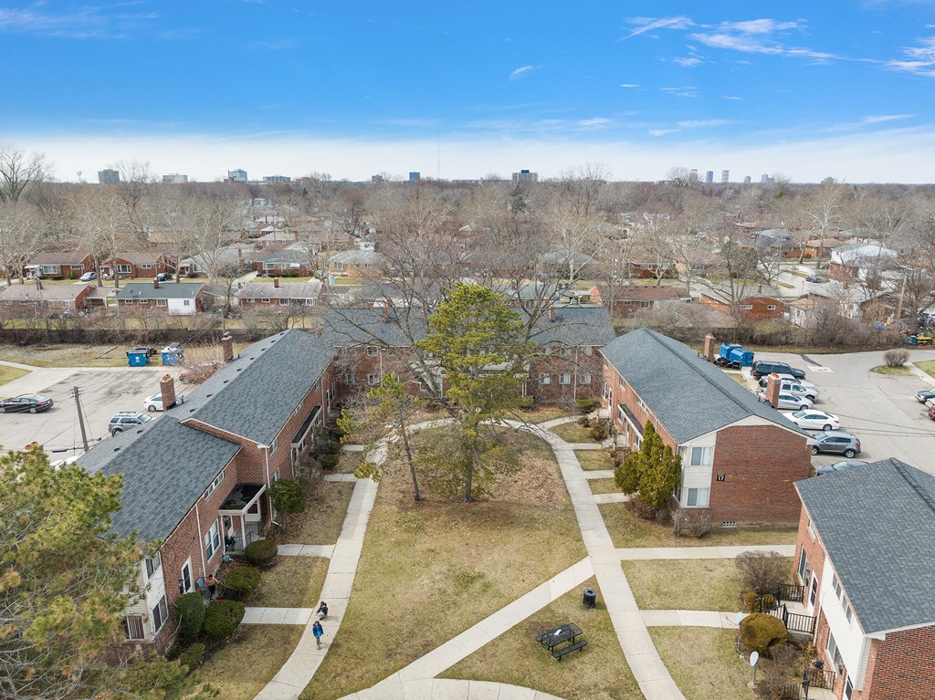 an aerial view of two brick buildings with gray roofs and a grassy area between them