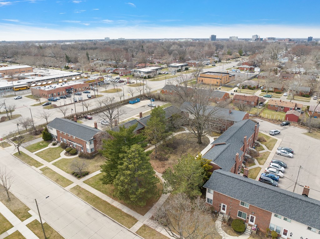 an aerial view of a brick building with a gray roof and a parking lot in front of
