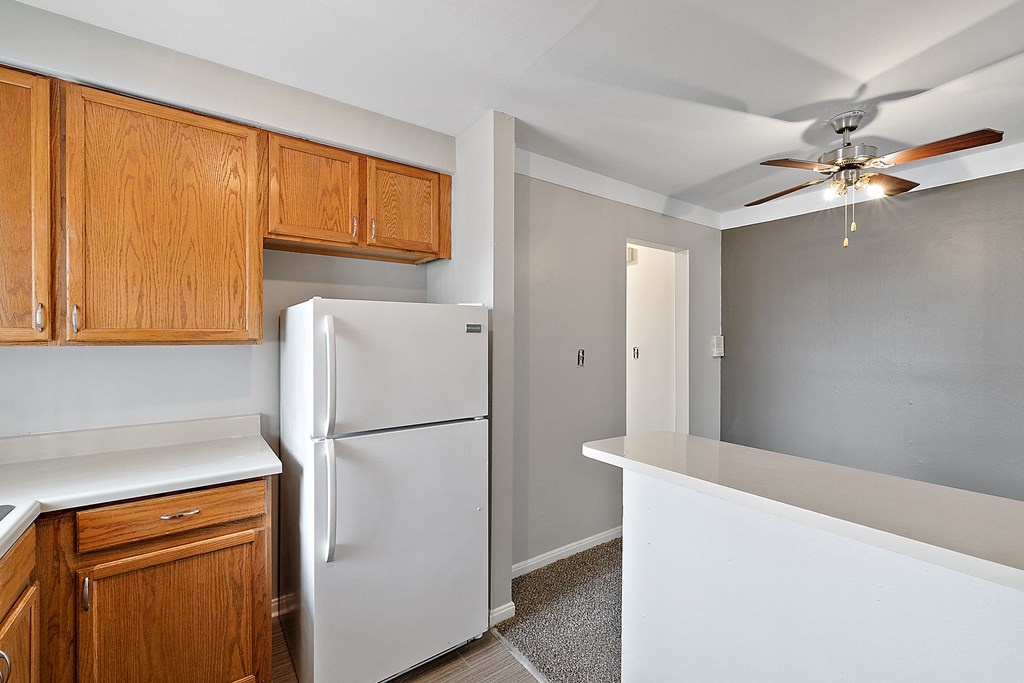 a kitchen with white countertops and wood cabinets