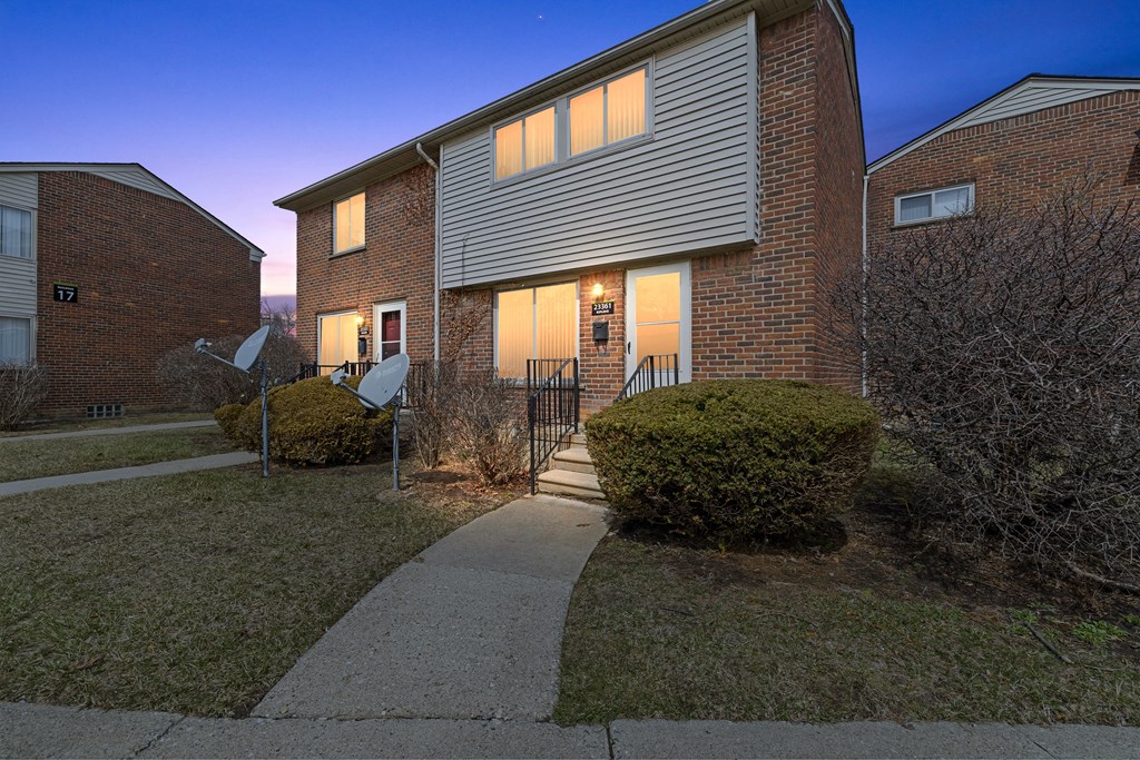a nighttime view of a brick apartment building with a sidewalk in front of it