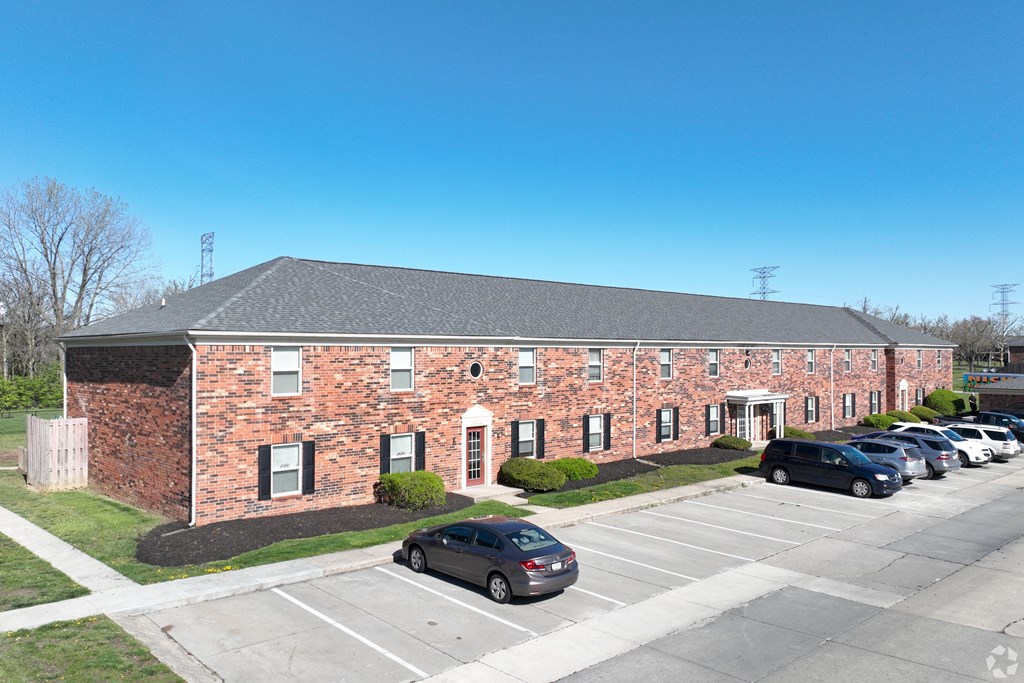 A brick building with a parking lot in front.