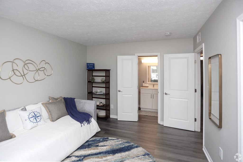 A white couch with a blue throw blanket and pillow with a blue design on it.