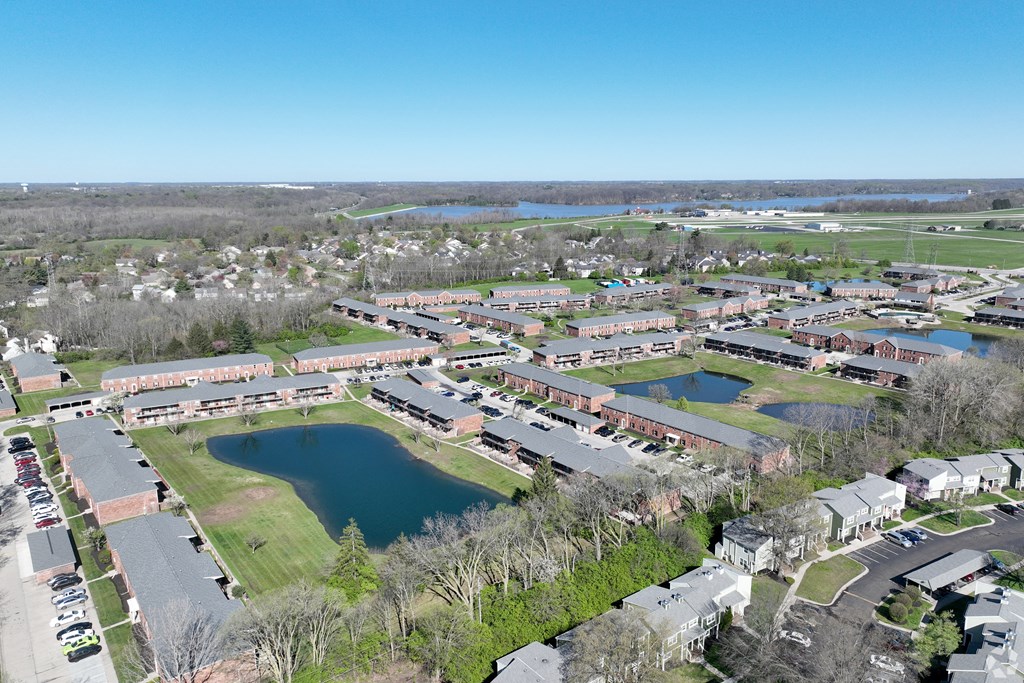A large building complex with a green field in front and a lake in the middle.