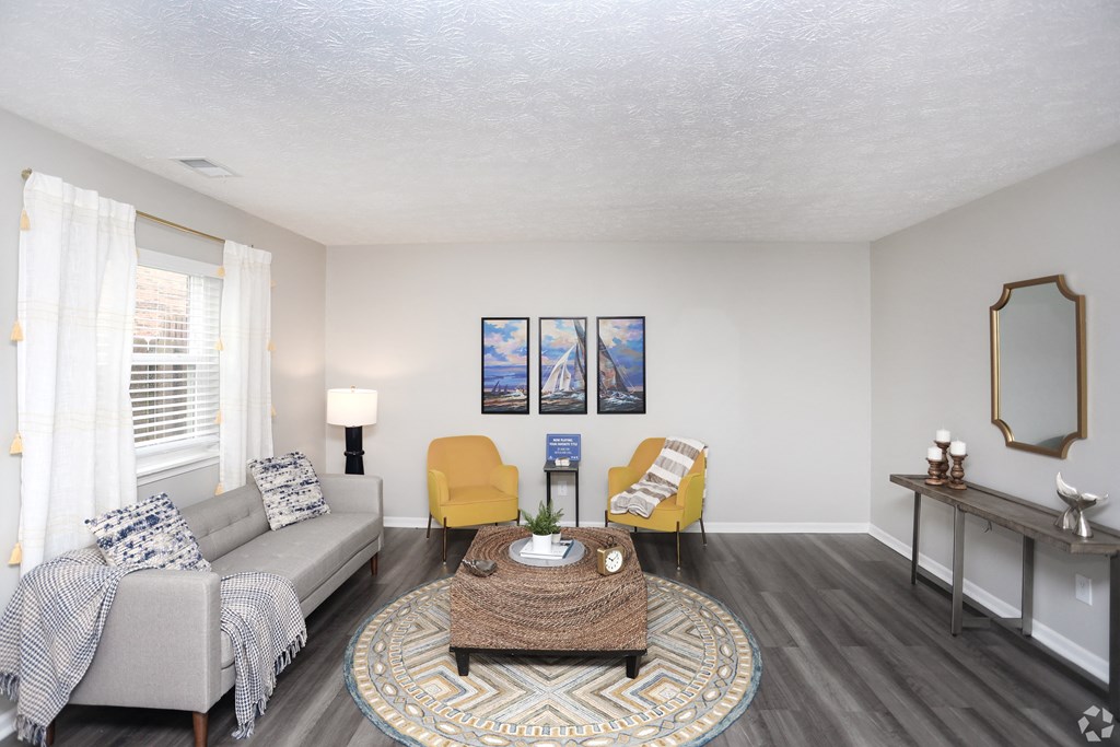 A living room with a grey couch, yellow chairs, and a coffee table.