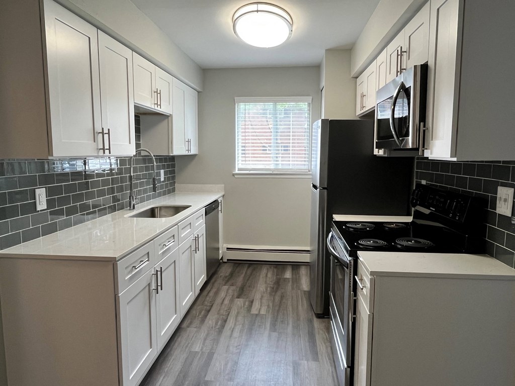 a kitchen with white cabinets and black appliances