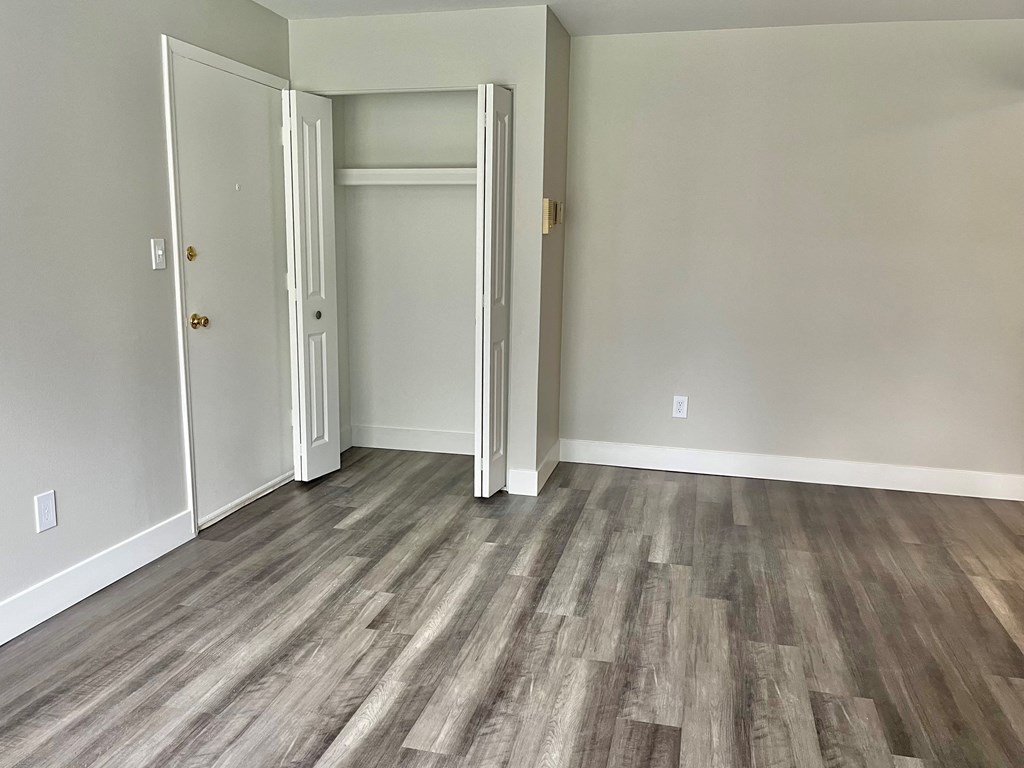 a bedroom with a hardwood floor and grey walls