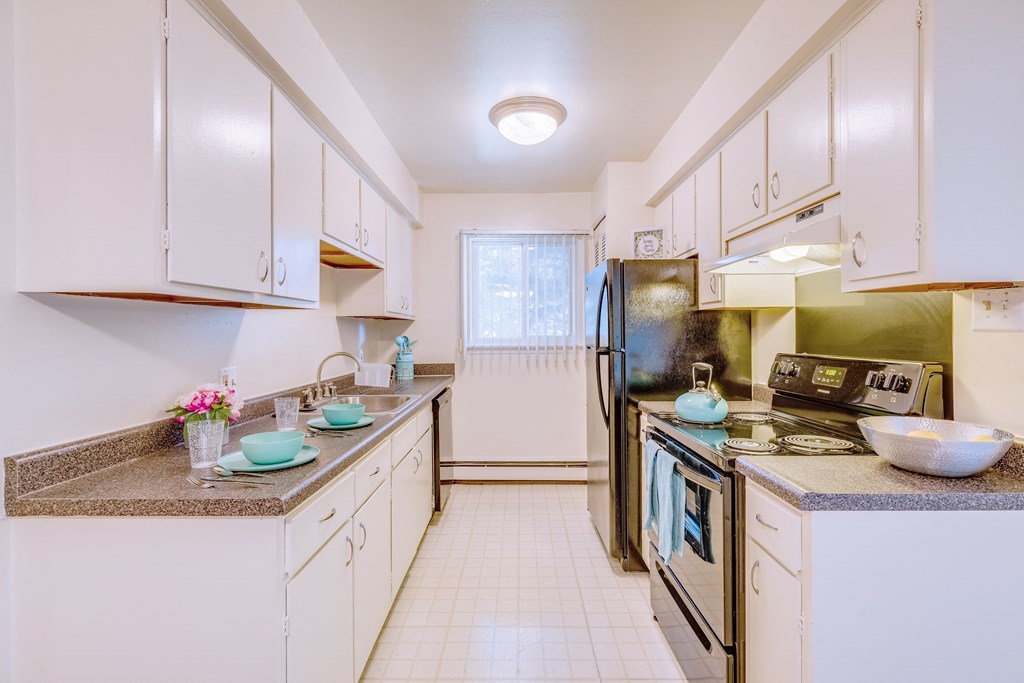 a kitchen with white cabinets and black appliances