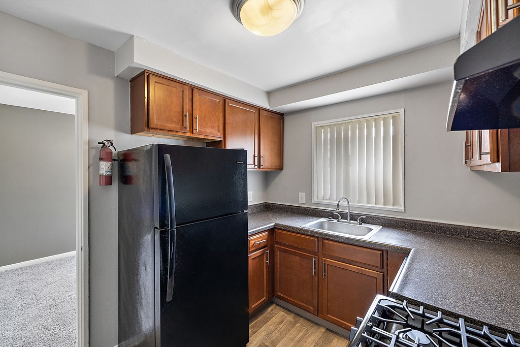a kitchen with a black refrigerator freezer next to a stove top oven