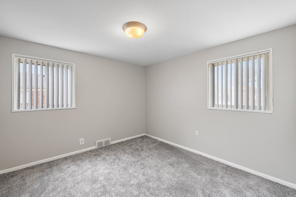 a bedroom with two windows and a carpeted floor