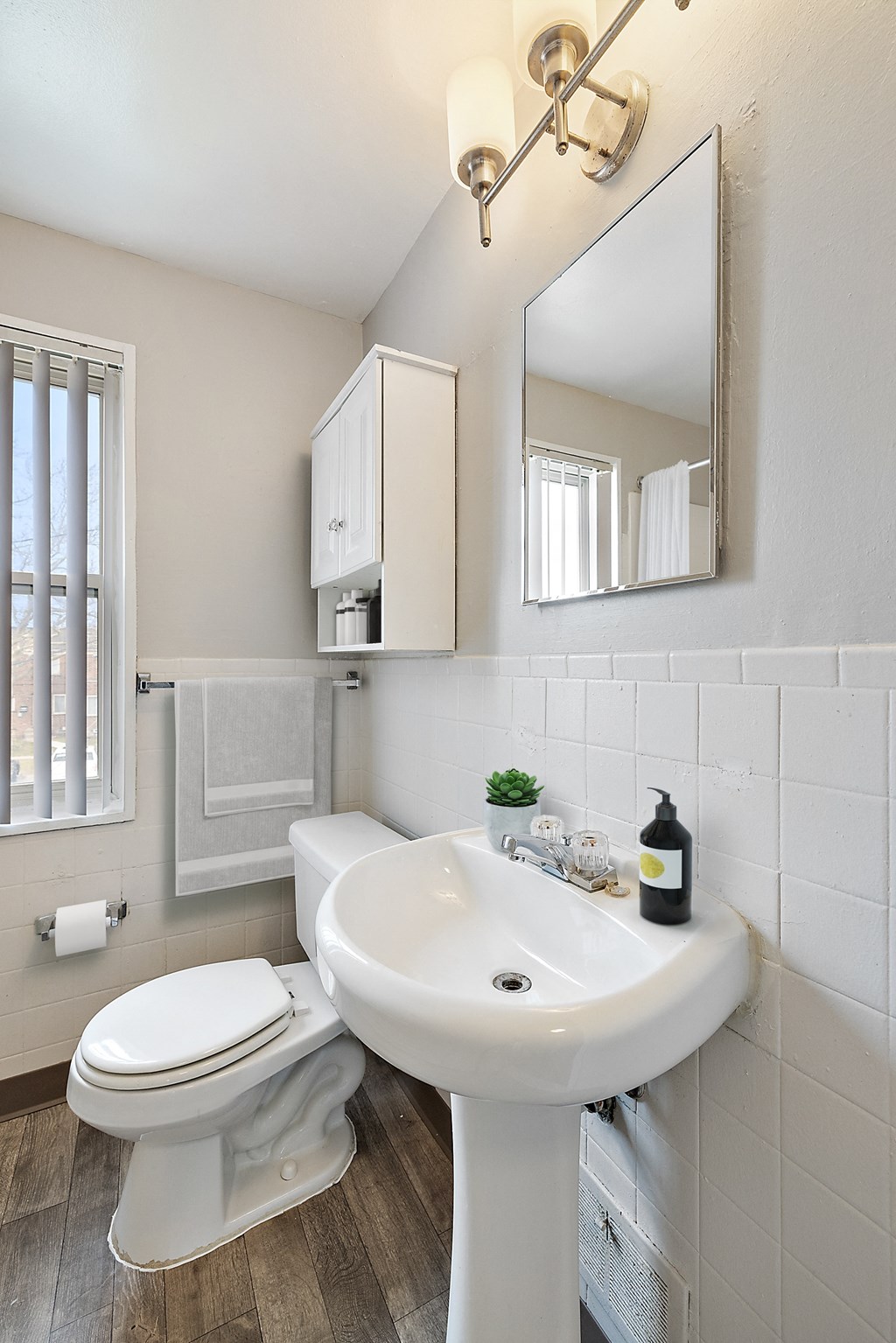 a bathroom with a white sink and toilet next to a window