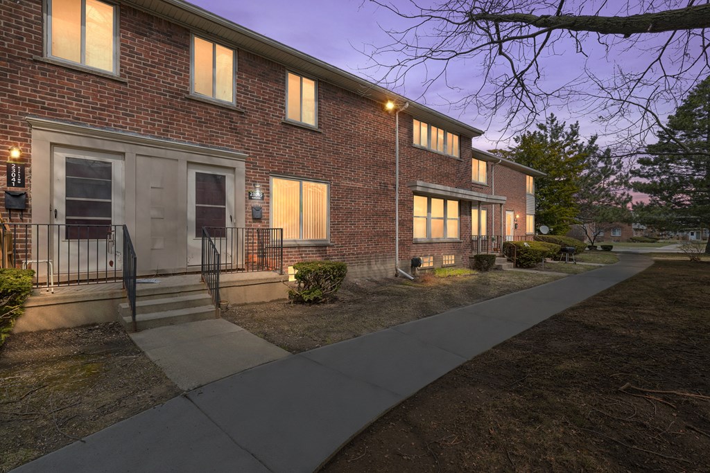 a nighttime view of a brick building with a sidewalk in front of it