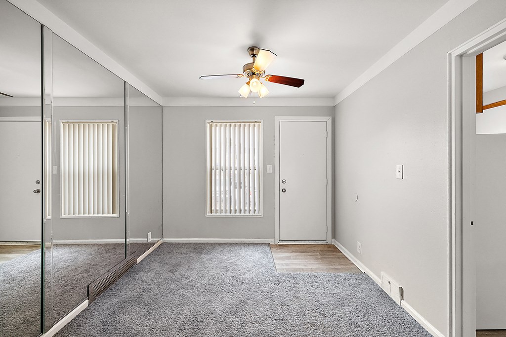 a bedroom with a ceiling fan and mirror