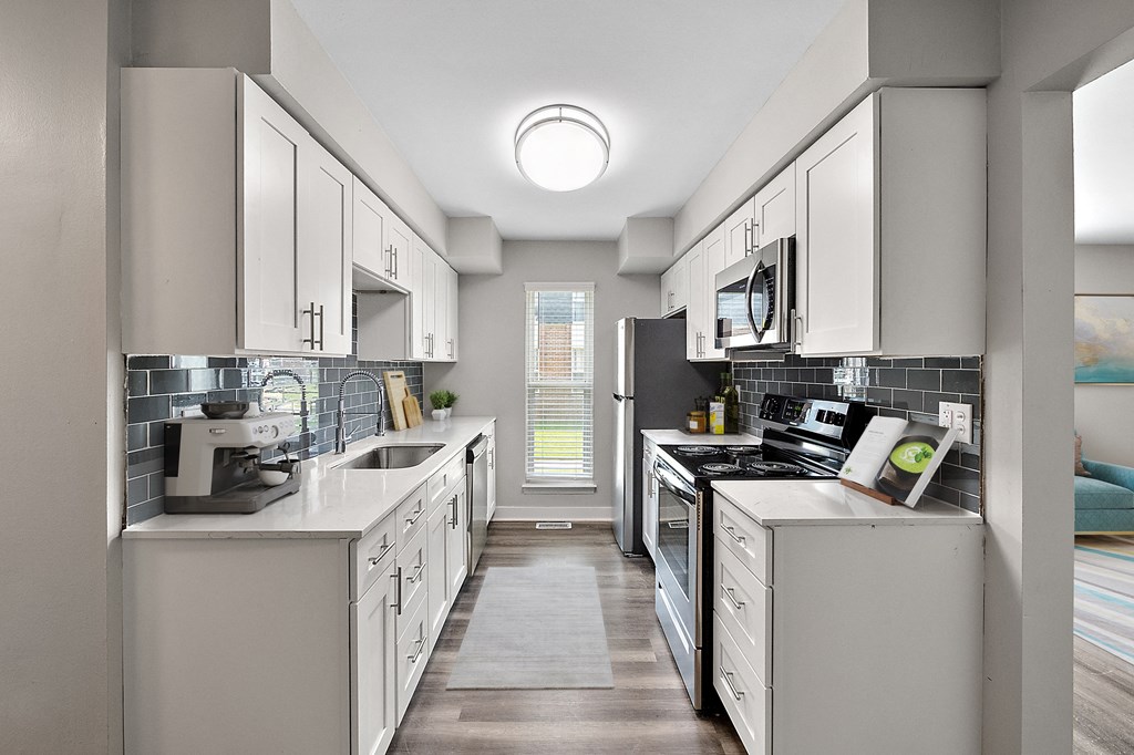 a kitchen with white cabinets and a wood floor
