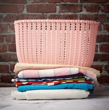 A pink basket is on top of a stack of folded towels.